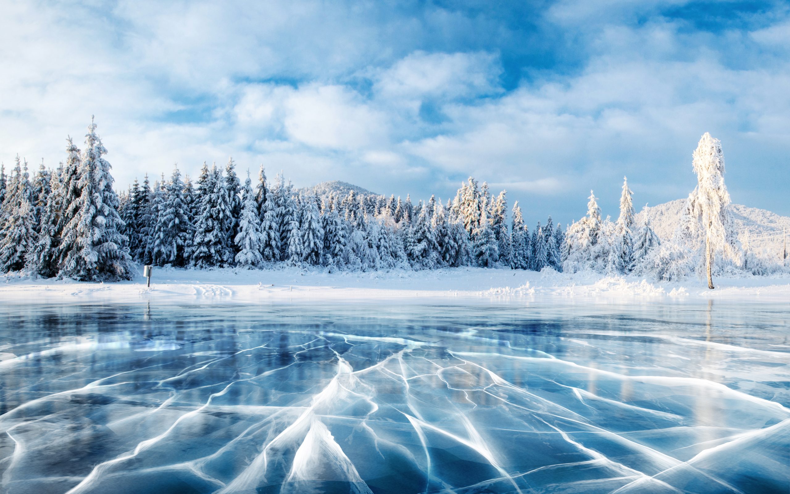 Luminen maisema, jonka keskiössä jäätynyt järvi ja sen ympärillä puita.