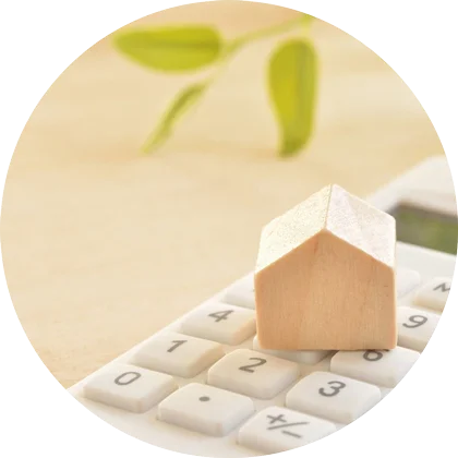 Kuvassa laskin ja sen päällä pieni puinen talo. Kuvan tarkoitus on kuvastaa talossa saatavia säästöjä lämpöpumpulla.