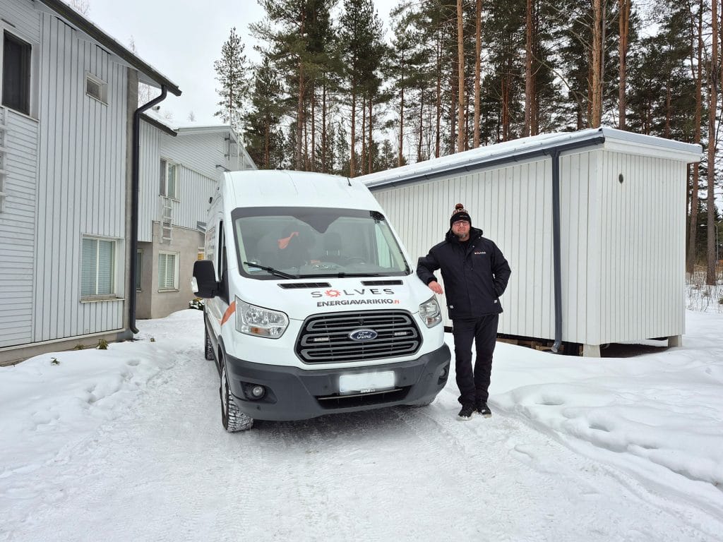 Jälleenmyyjä ja auto lumisessa maisemassa.