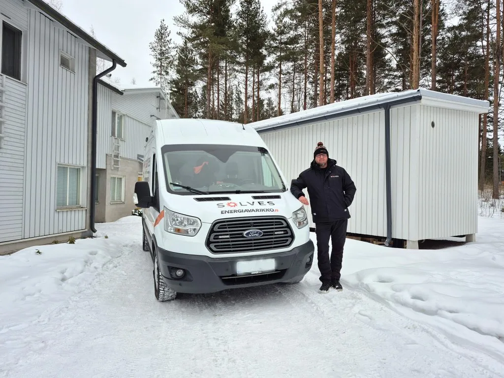 Jälleenmyyjä ja auto lumisessa maisemassa.