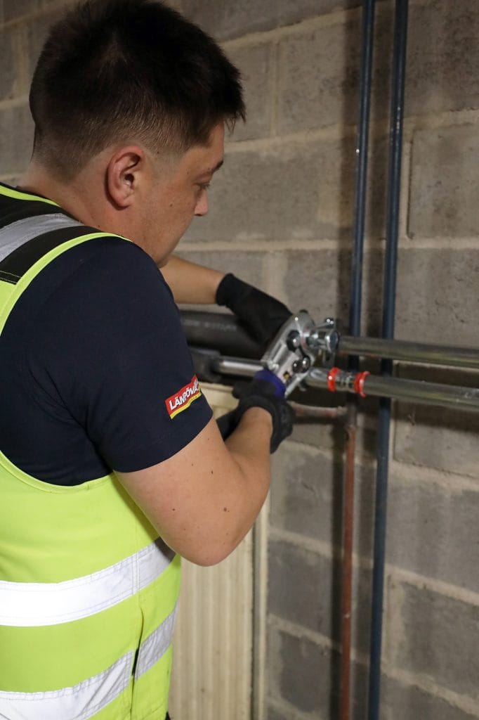 Mies asentaa maalämpöpumppua teknisessä tilassa.