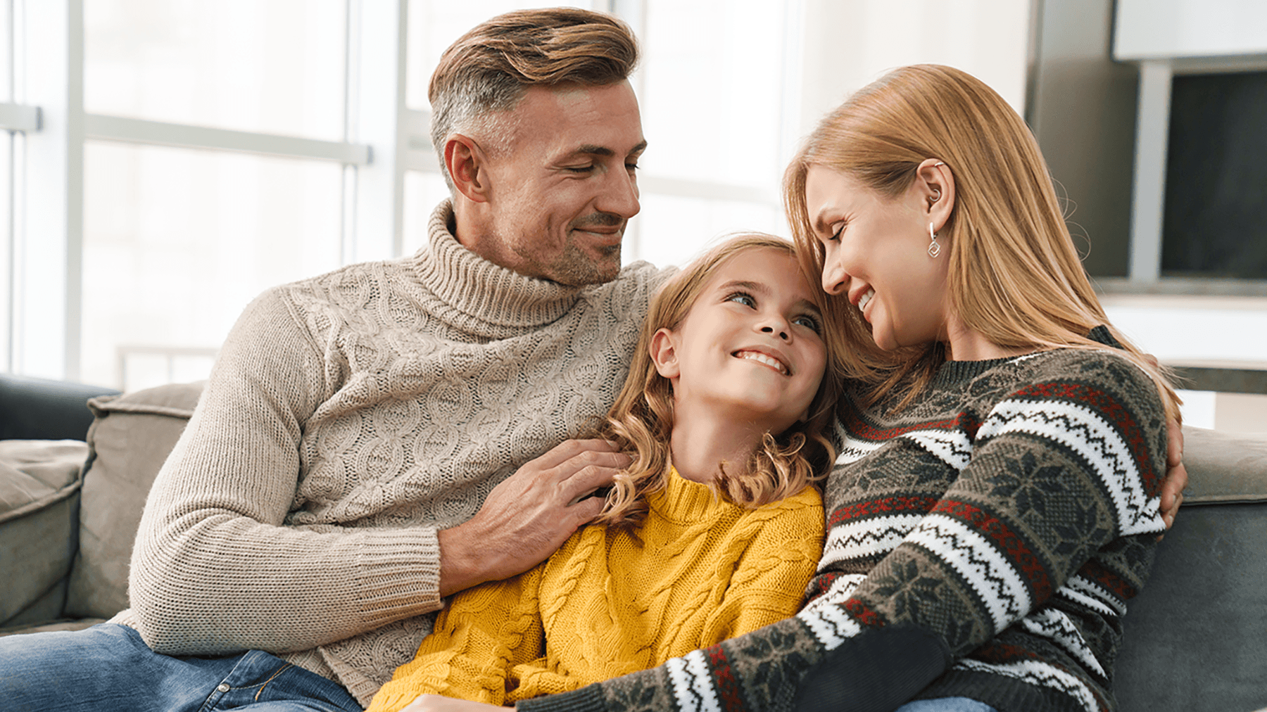 Perhe istuu sohvalla vierekkäin ja hymyilee toisilleen kuvituskuvassa.