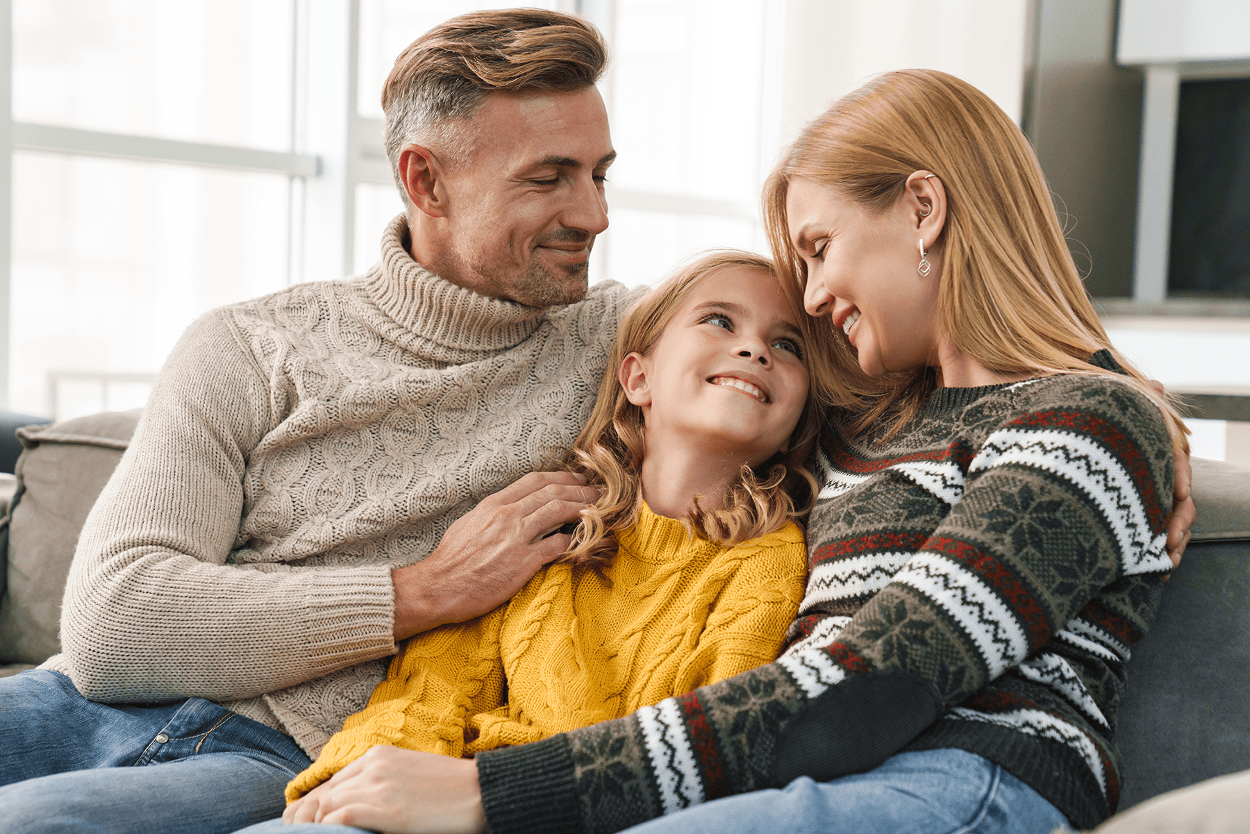 Perhe istuu sohvalla vierekkäin ja hymyilee toisilleen kuvituskuvassa.