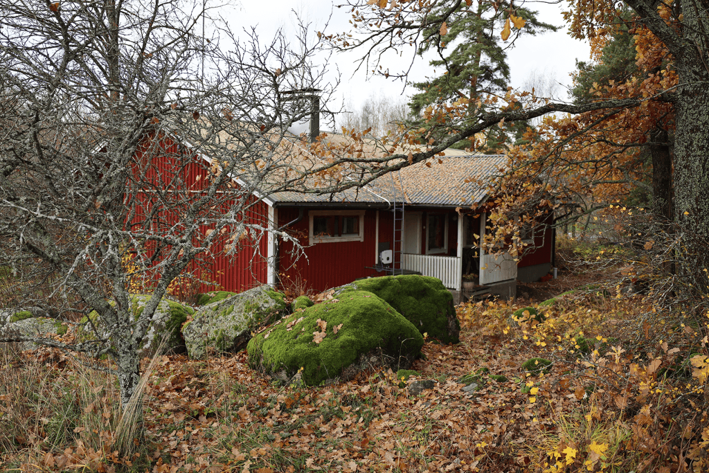 Punainen talo, johon asennettiin maalämpopumppu, syksyisessä maisemassa.