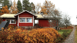 Punainen talo, johon asennettiin maalämpopumppu, syksyisessä maisemassa.