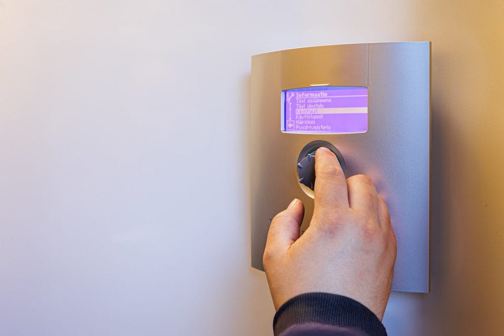 alpha innotec maalämpöpumpun hallinta, jota asentajan käsi käyttää.