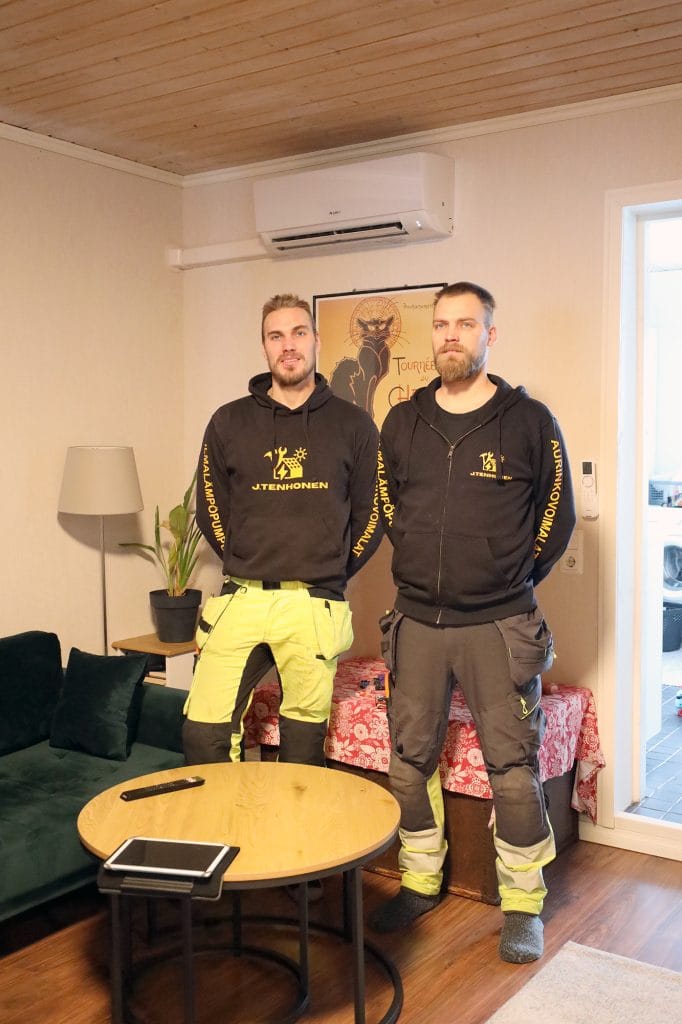 Ilmalämpöpumpun asentajat sisäyksikön edessä.
