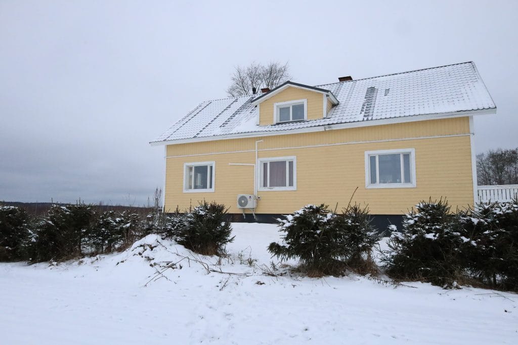Keltainen omakotitalo lumisessa maisemassa.